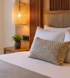 Detalle de la cama con cojín tejido y lámpara de mimbre
